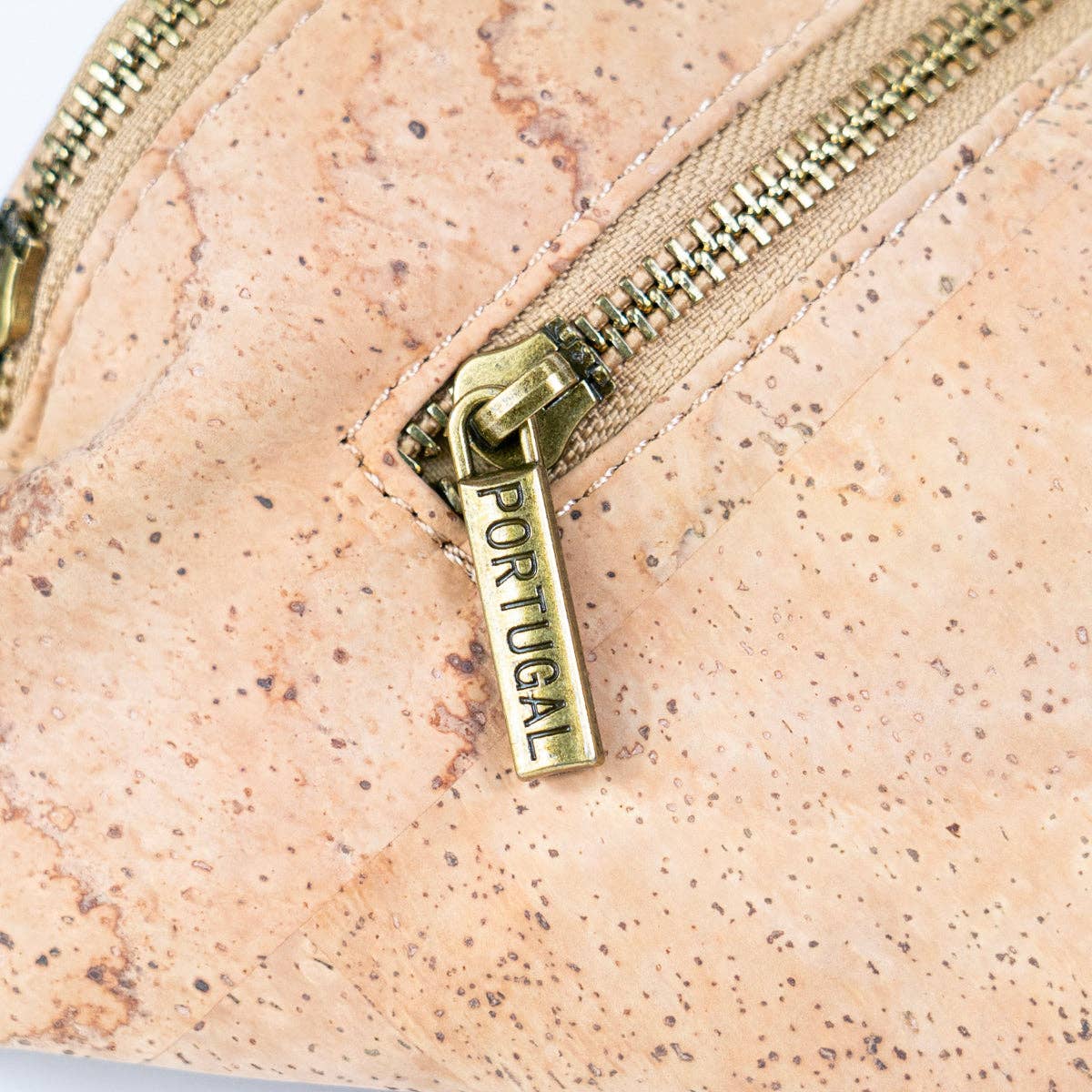 Close-up of cork sling bag craftsmanship, zipper, and logo